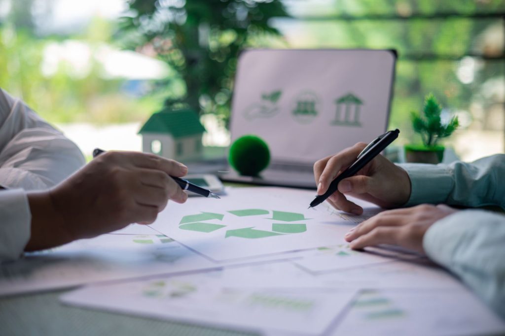 Pessoas planejando projeto com ícones de sustentabilidade, destacando a responsabilidade no design com propósito.